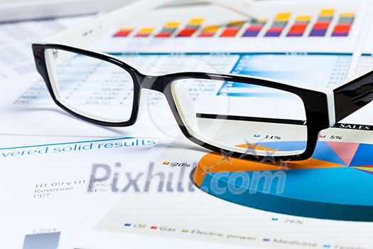 Eye glasses lying on papers with graphs and diagrams Eye glasses lying on papers with graphs and diagrams