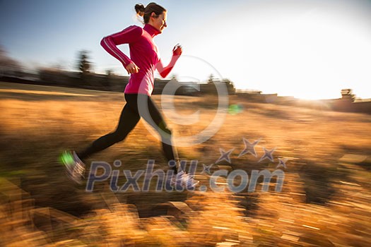 Young woman running outdoors on a lovely sunny winter/fall day (motion blurred image)