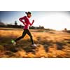 Young woman running outdoors on a lovely sunny winter/fall day (motion blurred image)