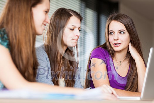 young pretty female college student sitting in a classroom full of students during class young pretty female college student sitting in a classroom full of students during class
