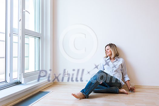 Just moved in: beautiful young woman having a drink in her brand new modern apartment