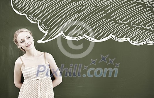 Young attractive thoughtful woman in dress standing at blackboard Young attractive thoughtful woman in dress standing at blackboard