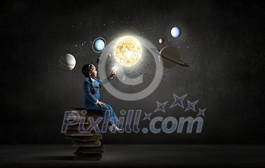 Little girl sitting on stack of books and touching planet