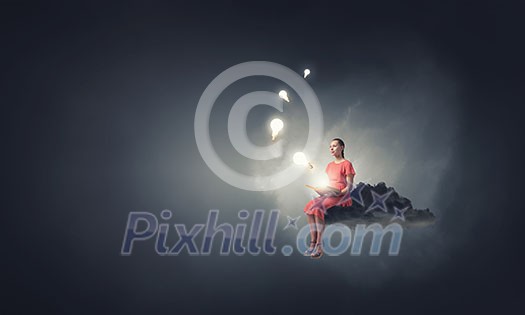 Young woman in dress with old book in hand sitting on cloud