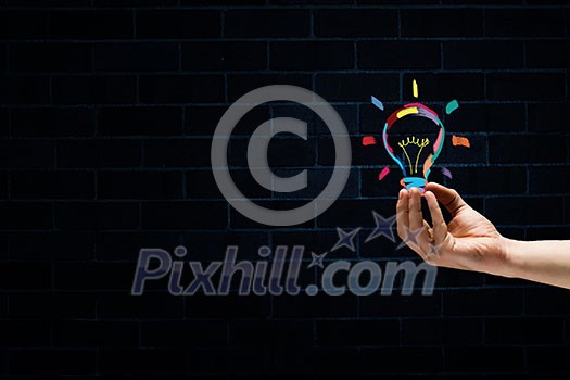 Male hand on dark background showing drawn light bulb Male hand on dark background showing drawn light bulb