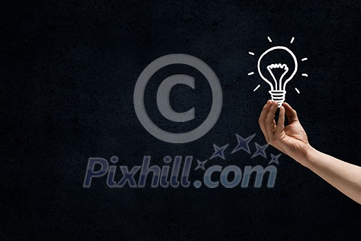 Male hand on dark background showing drawn light bulb Male hand on dark background showing drawn light bulb