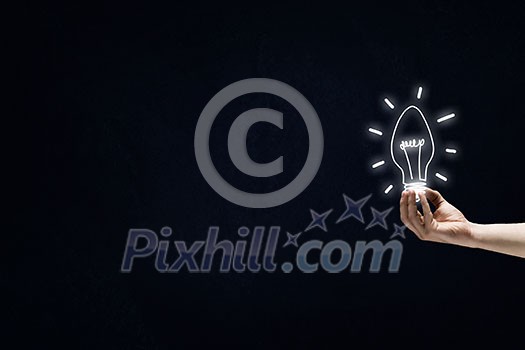 Male hand on dark background showing drawn light bulb Male hand on dark background showing drawn light bulb