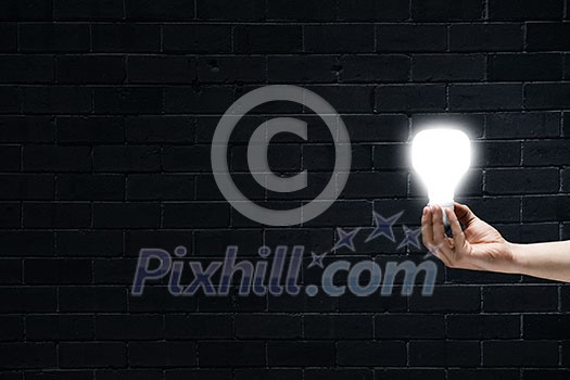 Male hand on dark background showing glass light bulb Male hand on dark background showing glass light bulb