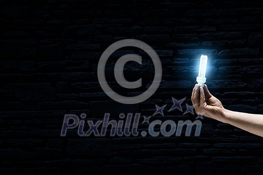 Male hand on dark background showing glass light bulb Male hand on dark background showing glass light bulb