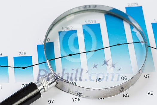 Magnifing glass and documents with analytics data lying on table