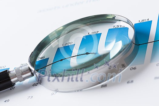 Magnifing glass and documents with analytics data lying on table Magnifing glass and documents with analytics data lying on table