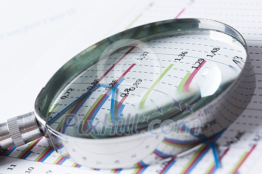 Magnifing glass and documents with analytics data lying on table Magnifing glass and documents with analytics data lying on table
