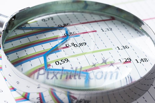 Magnifing glass and documents with analytics data lying on table Magnifing glass and documents with analytics data lying on table