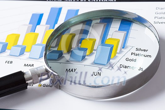 Magnifing glass and documents with analytics data lying on table Magnifing glass and documents with analytics data lying on table