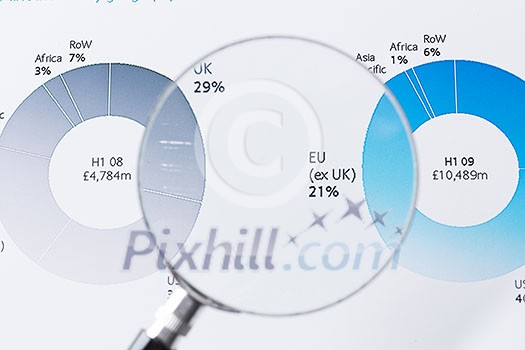 Magnifing glass and documents with analytics data lying on table Magnifing glass and documents with analytics data lying on table
