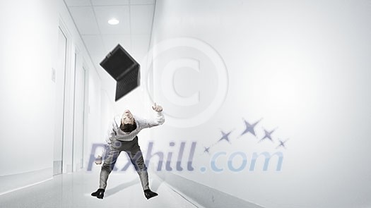 Young businessman evading back from flying laptop