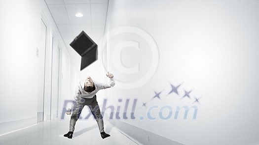 Young businessman evading back from flying laptop Young businessman evading back from flying laptop