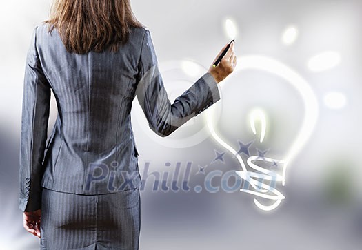 Rear view of businesswoman touching light bulb Rear view of businesswoman touching light bulb