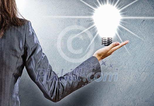 Rear view of businesswoman holding light bulb in palm Rear view of businesswoman holding light bulb in palm