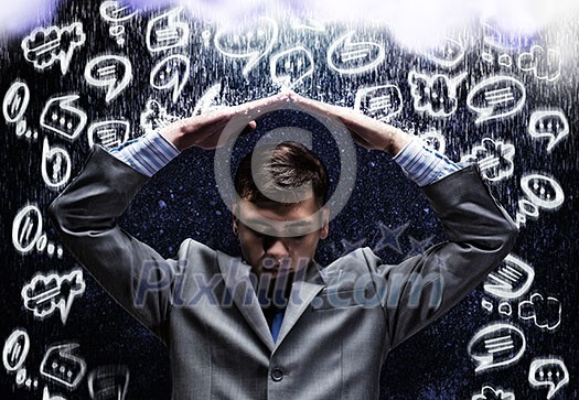 Young businessman under rain covering head with hands