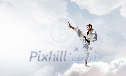 Young determined karate man on cloud high in sky Young determined karate man on cloud high in sky