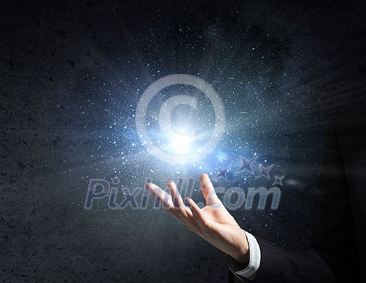 Businessman holding light flash in palm on dark background Businessman holding light flash in palm on dark background