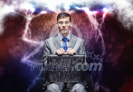 Young businessman under rain sitting on chain