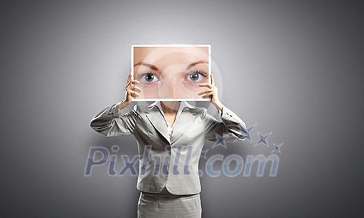 Businesswoman hiding face behind photo of eyes Businesswoman hiding face behind photo of eyes