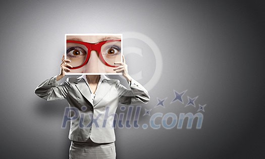 Businesswoman hiding face behind photo of eyes Businesswoman hiding face behind photo of eyes