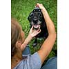 Younf woman combing out the fur of a black dog in her garden