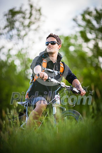 Handsome young man biking in the countryside