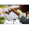 Male violinist playing his instrument and reading a music sheet during an outdoor summer wedding ceremony (shallow DOF; color toned image)