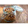 Homemade granola in open glass jar on rustic wooden background
