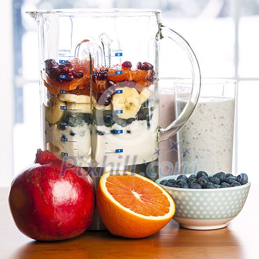 Prepared smoothies and healthy smoothie ingredients in blender with fresh fruit ready to blend on kitchen table Prepared smoothies and healthy smoothie ingredients in blender with fresh fruit ready to blend on kitchen table