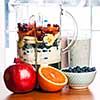 Prepared smoothies and healthy smoothie ingredients in blender with fresh fruit ready to blend on kitchen table
