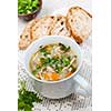 Cup of hot chicken rice soup served with bread and parsley on crochet tablecloth