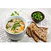 Cup of hot chicken rice soup served with bread and parsley on crochet tablecloth