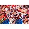 Red shoes standing in many fallen maple leaves from above