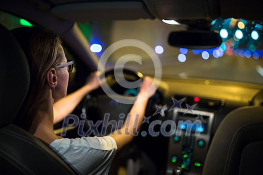 Female drive driving a car at night (shallow DOF; colour toned image)