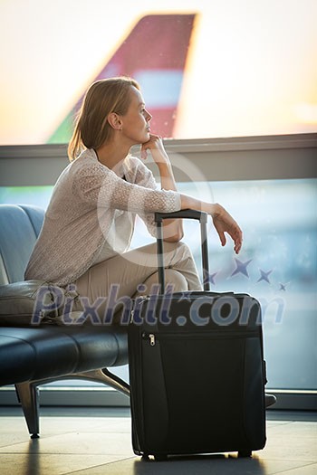 Young female passenger at the airport, waiting for her flight boarding call (color toned image; shallow DOF)