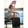 Young female passenger at the airport, waiting for her flight boarding call (color toned image; shallow DOF)