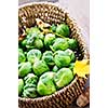 Basket of green brussels sprouts with autumn leaves