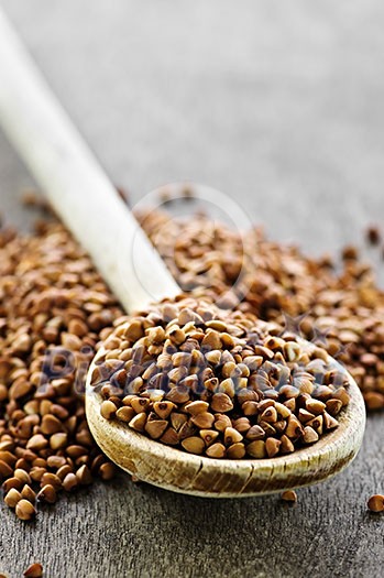 Buckwheat seeds on wooden spoon in closeup Buckwheat seeds on wooden spoon in closeup