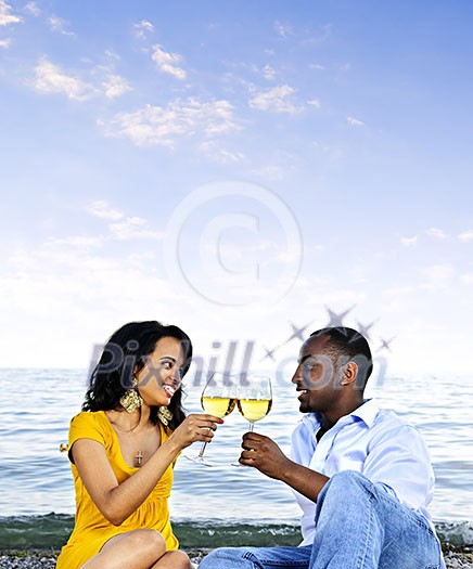 Young romantic couple celebrating with wine at the beach with copyspace