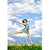 Young teenage girl jumping in summer meadow amid wildflowers
