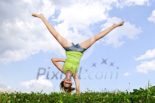 Young teenage girl doing cartwheel in a summer meadow