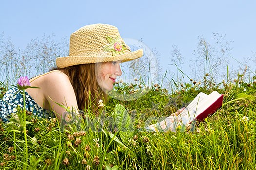 Young teenage girl reading book in summer meadow with straw hat Young teenage girl reading book in summer meadow with straw hat