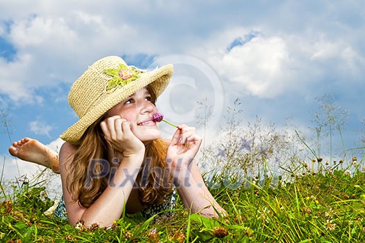 Young teenage girl laying in summer meadow resting chin on hand smelling flower Young teenage girl laying in summer meadow resting chin on hand smelling flower