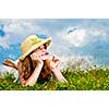 Young teenage girl laying in summer meadow resting chin on hand smelling flower