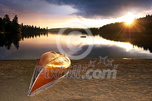 Sun setting over tranquil lake with canoe on beach